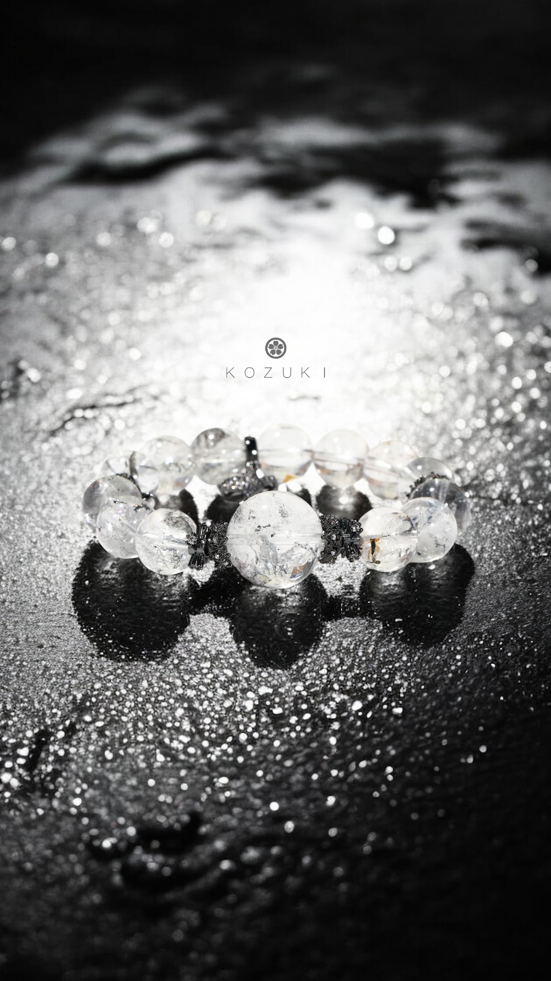 clear crystal bracelet with phantom quartz and black crown on shimmering dark surface