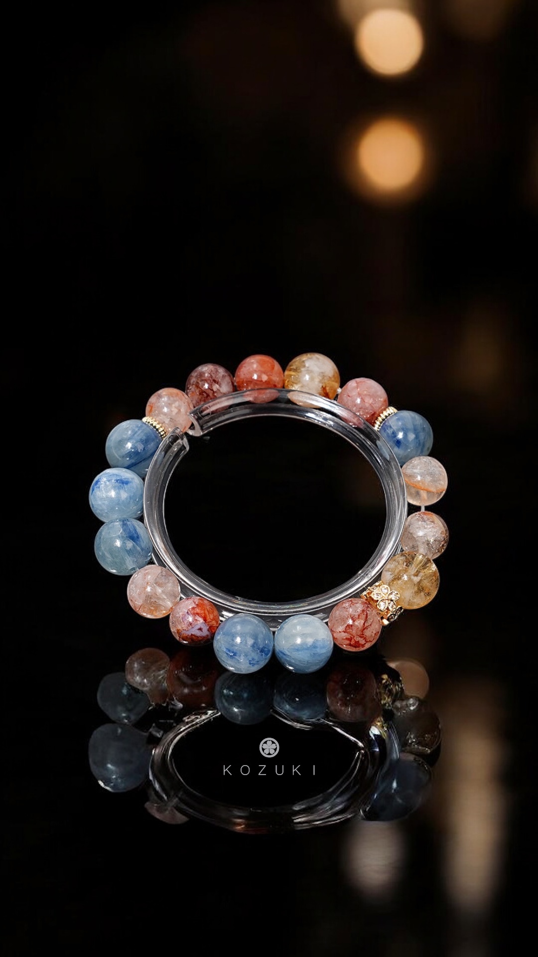 Coral Ocean red and blue gem bracelet in soft light over black marble surface