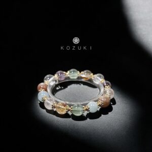 KOZUKI crystal bracelet with natural gemstones and gold accents lit by soft studio light