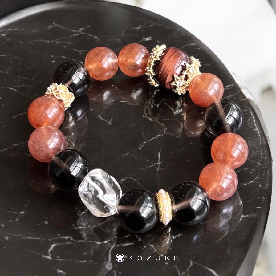 Red crystal bracelet with red tiger’s eye centerpiece on black marble table