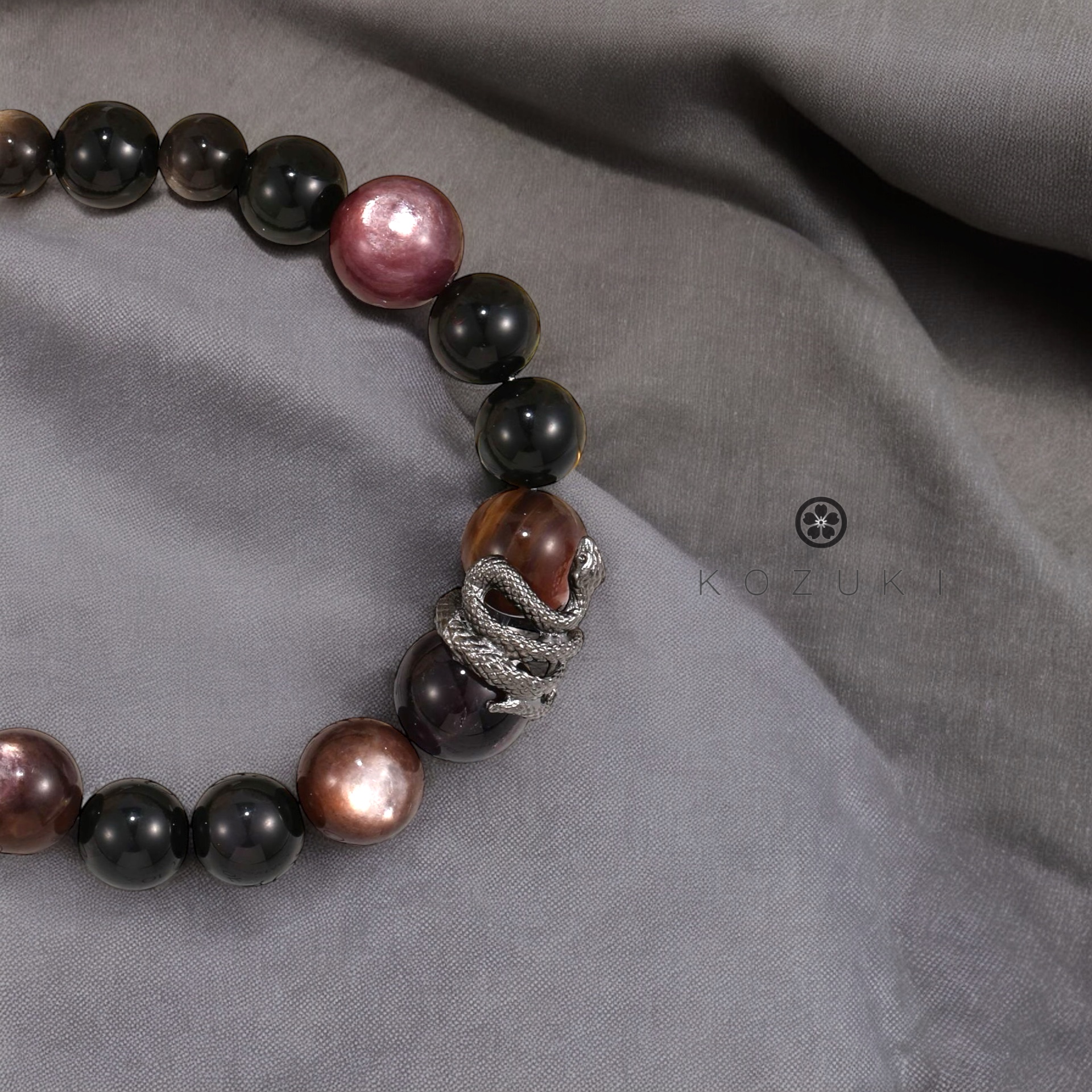 Black and purple snake crystal bracelet displayed on black and white satin, reflecting mystical energy