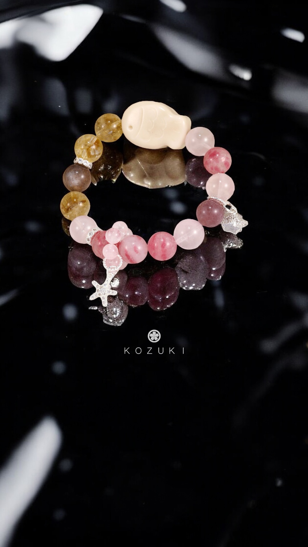 Yellow and pink gemstone bracelet styled with hanami vibes, glowing gently on reflective black surface.