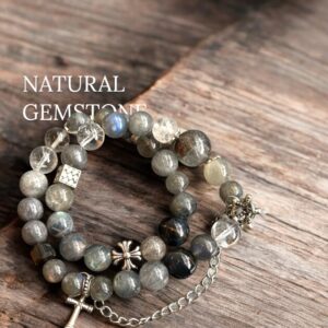 Rutilated quartz and labradorite gemstone bracelet featuring moonstone beads and silver gothic charms, styled on rustic wood surface