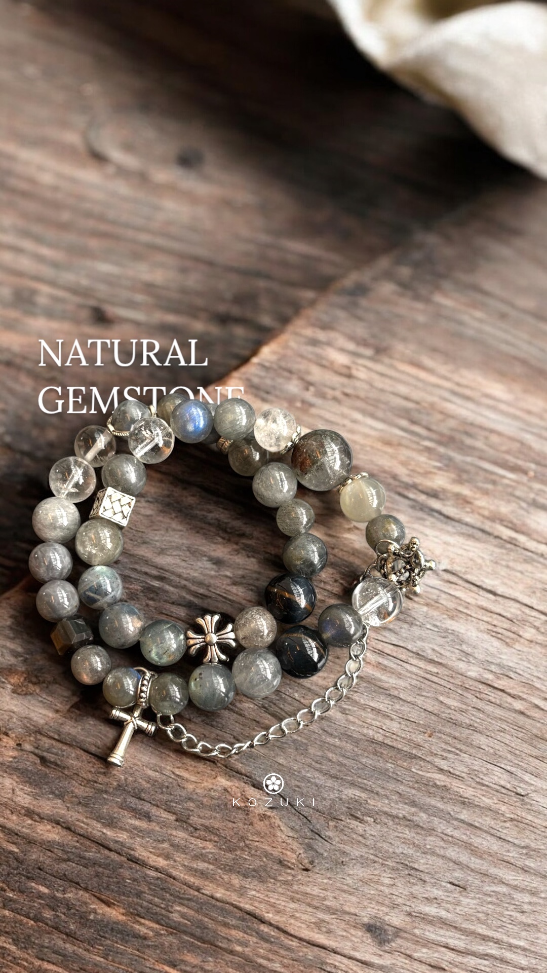 Rutilated quartz and labradorite gemstone bracelet featuring moonstone beads and silver gothic charms, styled on rustic wood surface
